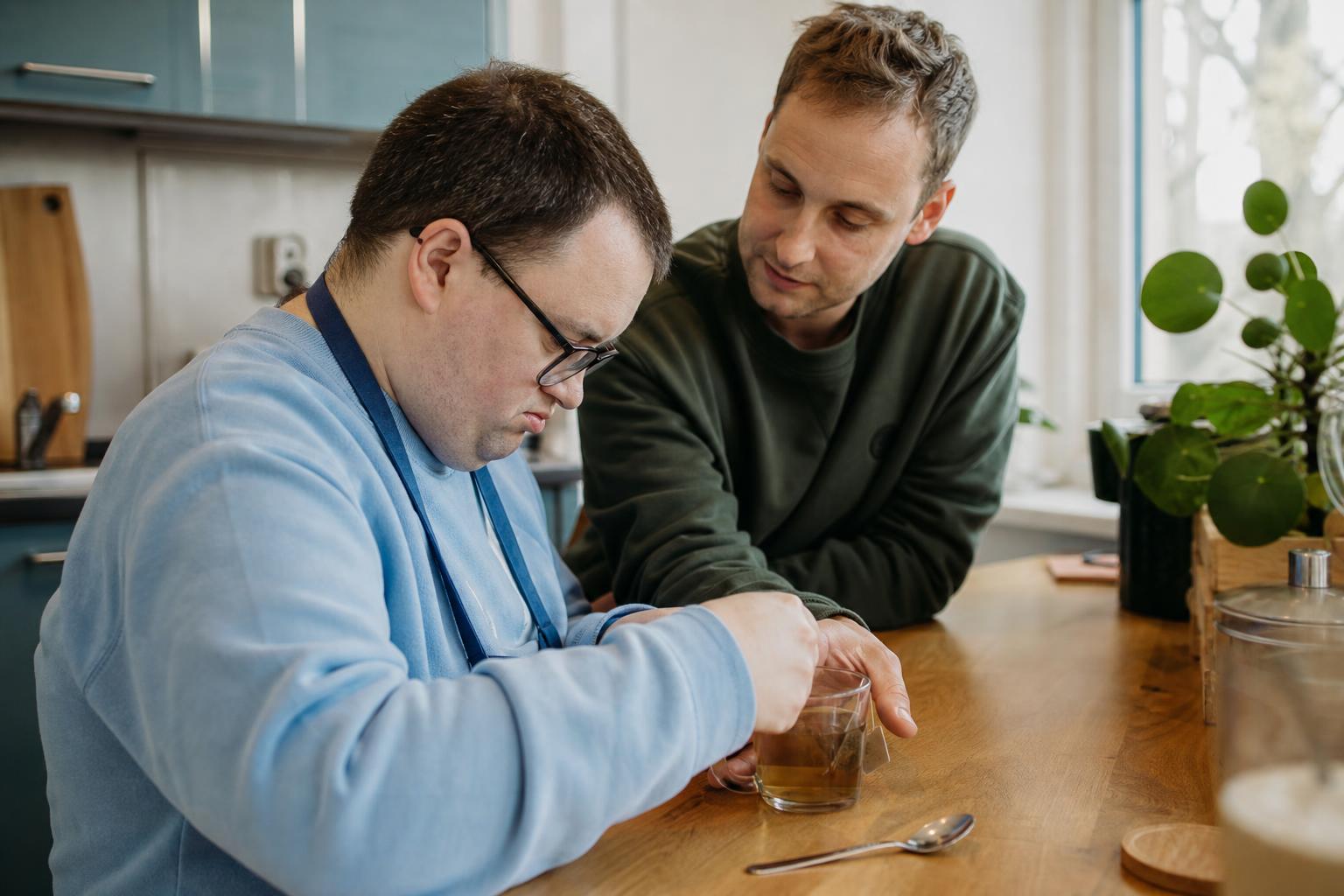 Begeleider ondersteunt een cliënt bij een dagelijkse activiteit in een huiselijke keuken